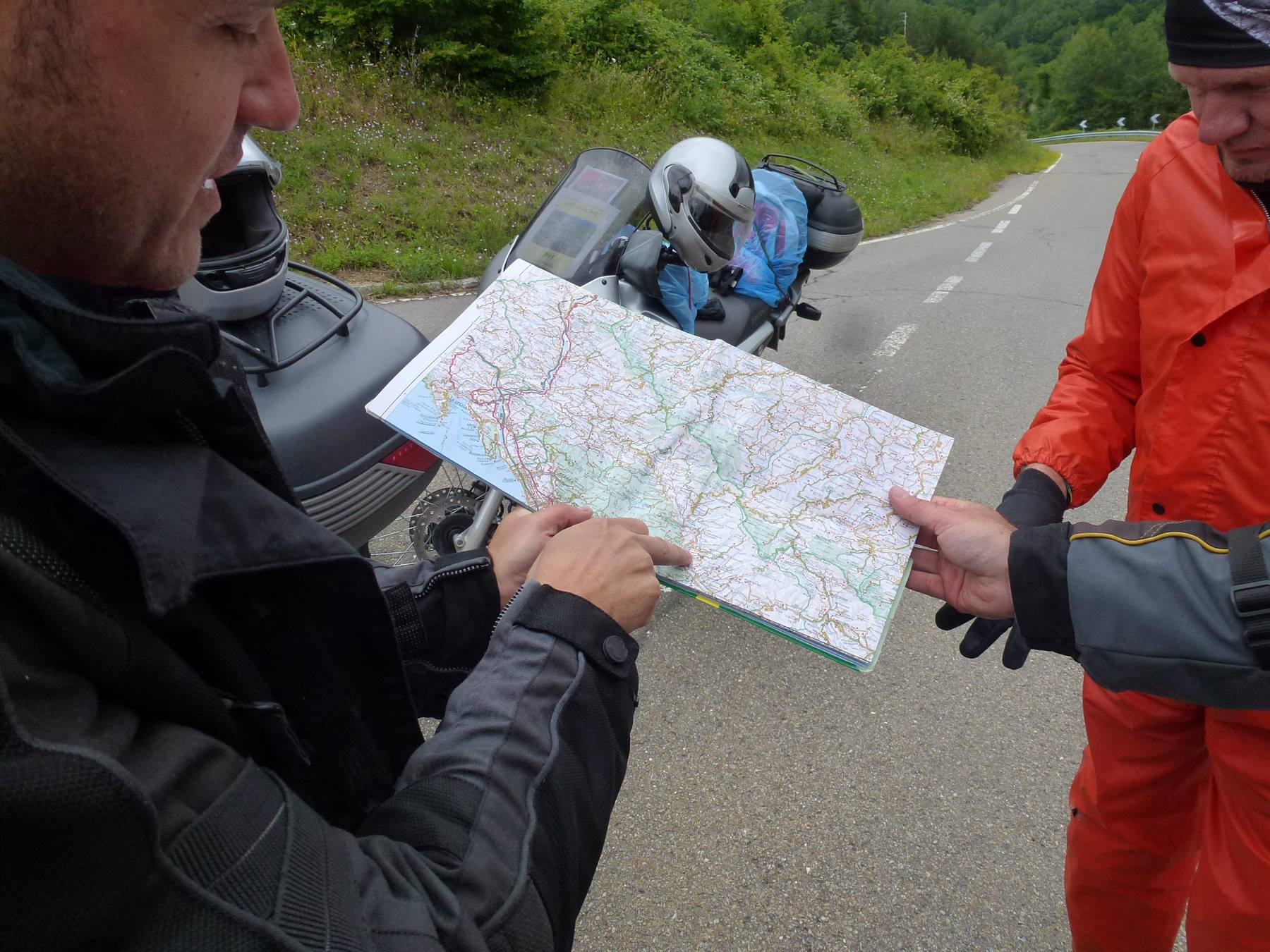 Due motociclisti consultano una carta stradale accanto alle moto parcheggiate