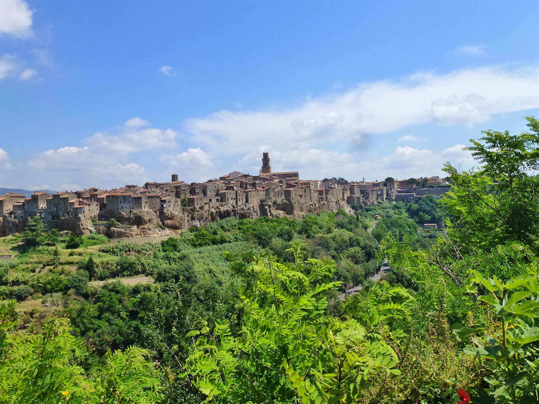 Pitigliano, case di tufo sul ciglio della rupe sotto il cielo azzurro