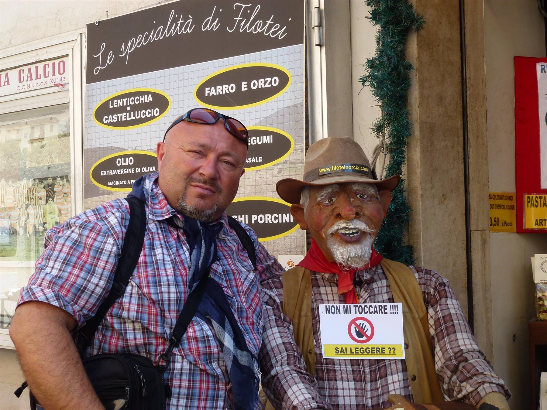 Uomo accanto a una statua di cowboy davanti al negozio Le specialità di Filotei