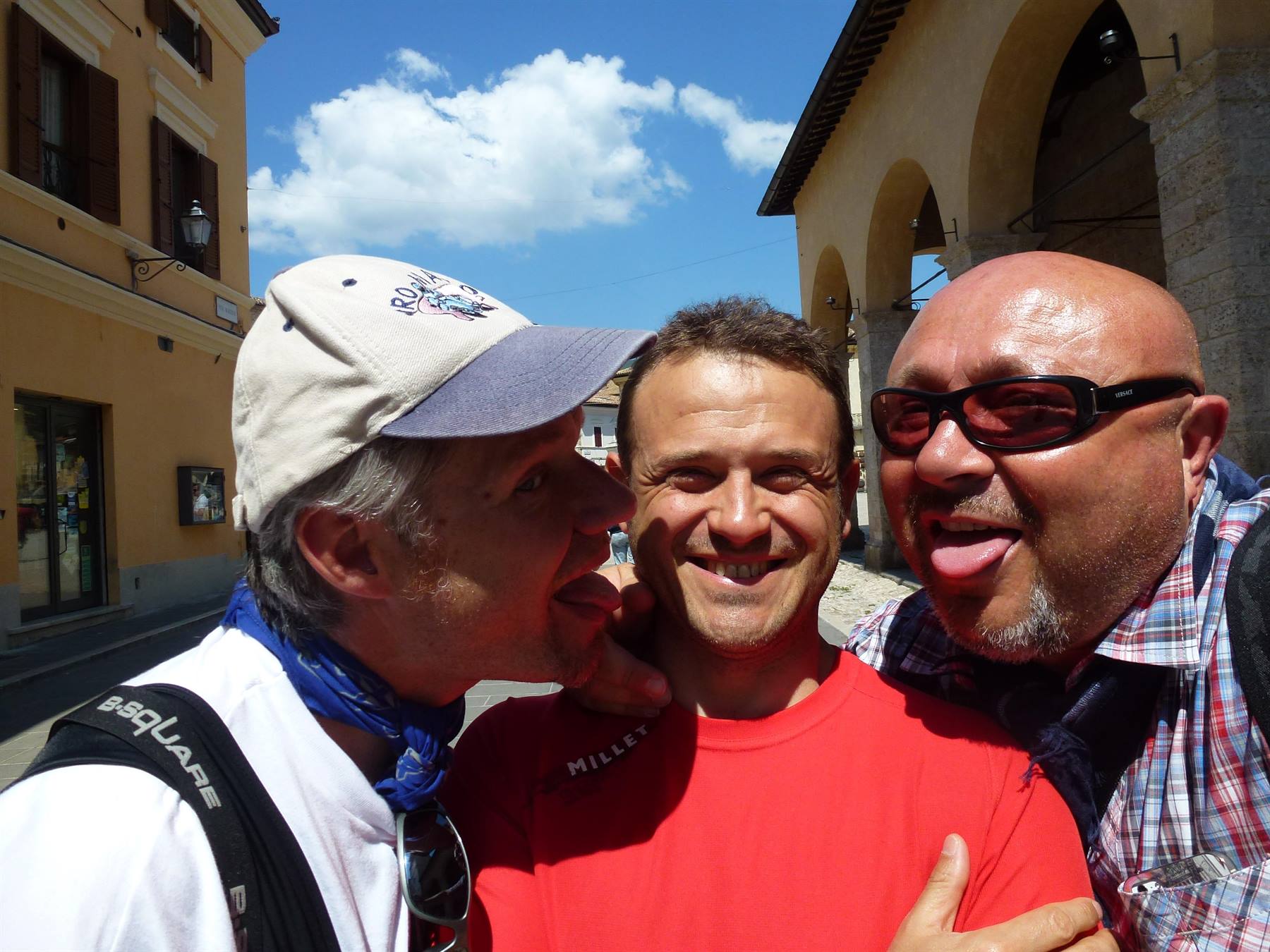 Tre amici scherzano sotto i portici di un borgo medievale al sole