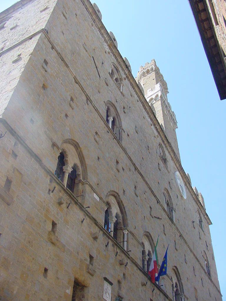 Palazzo Vecchio a Firenze, facciata in pietra con torre merlata e bandiere