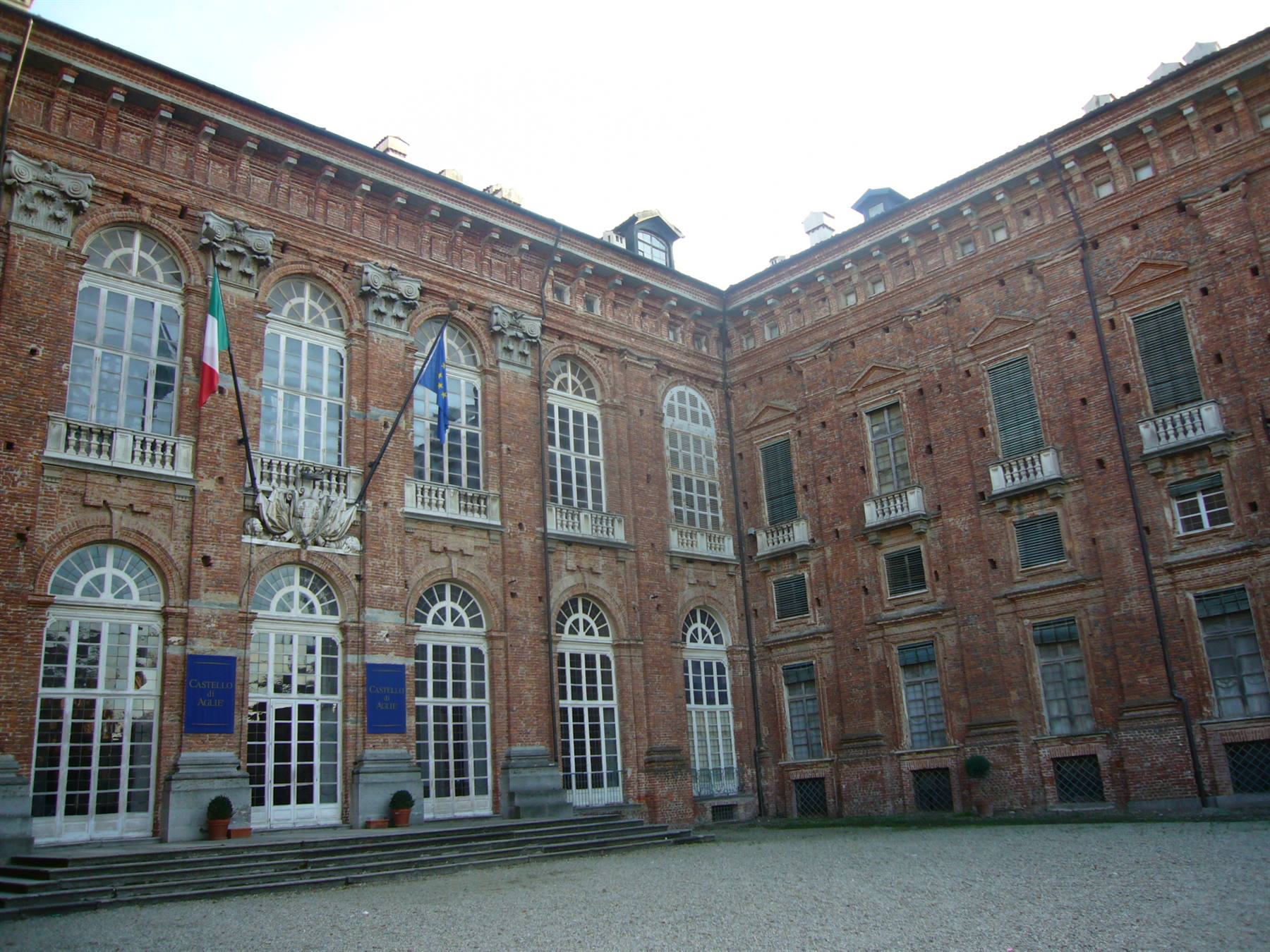 Cortile della Reggia di Venaria Reale, facciata in mattoni con bandiere italiana ed europea
