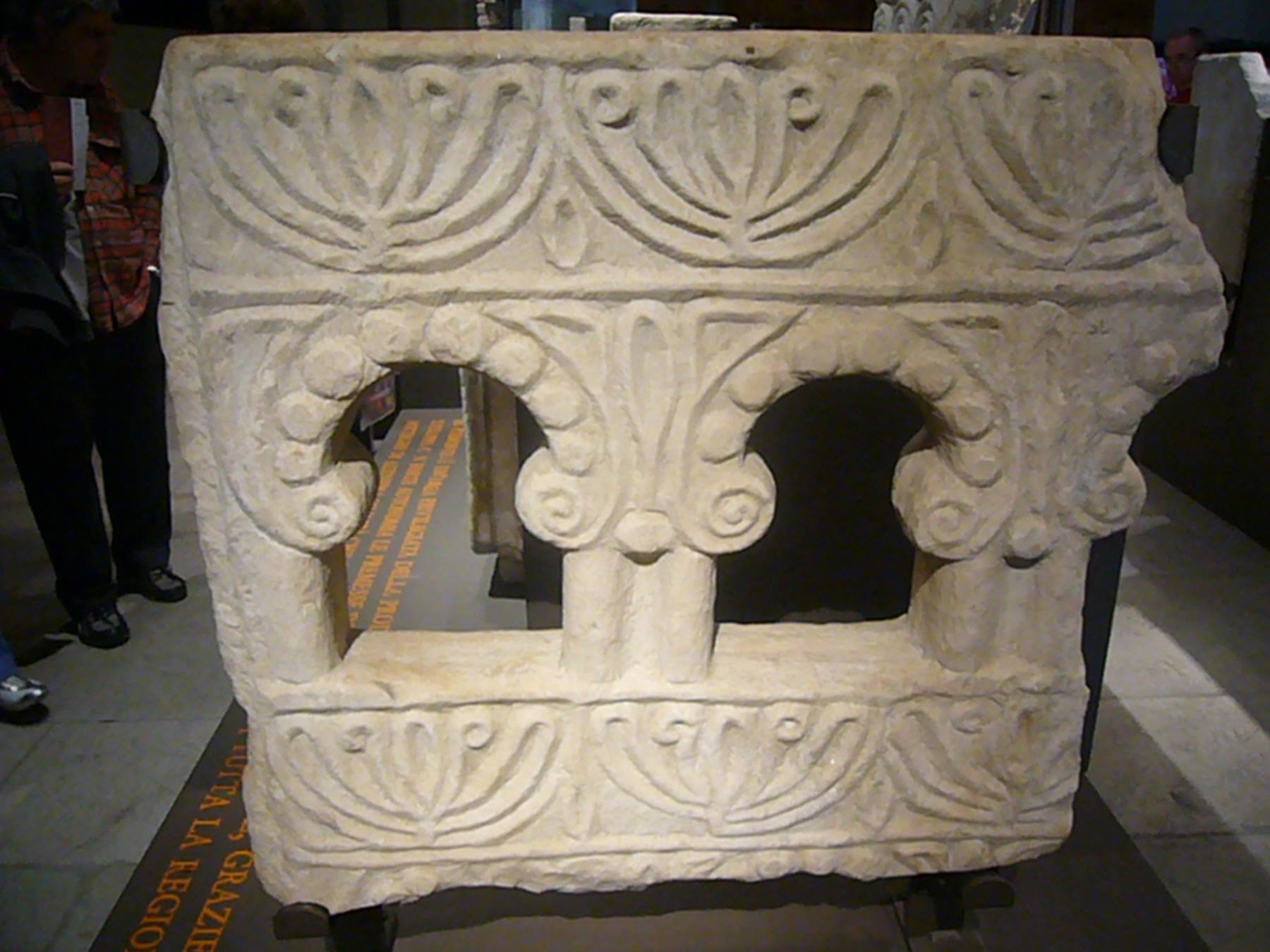 Plastro in pietra scolpita con archi e palme, esposto in museo