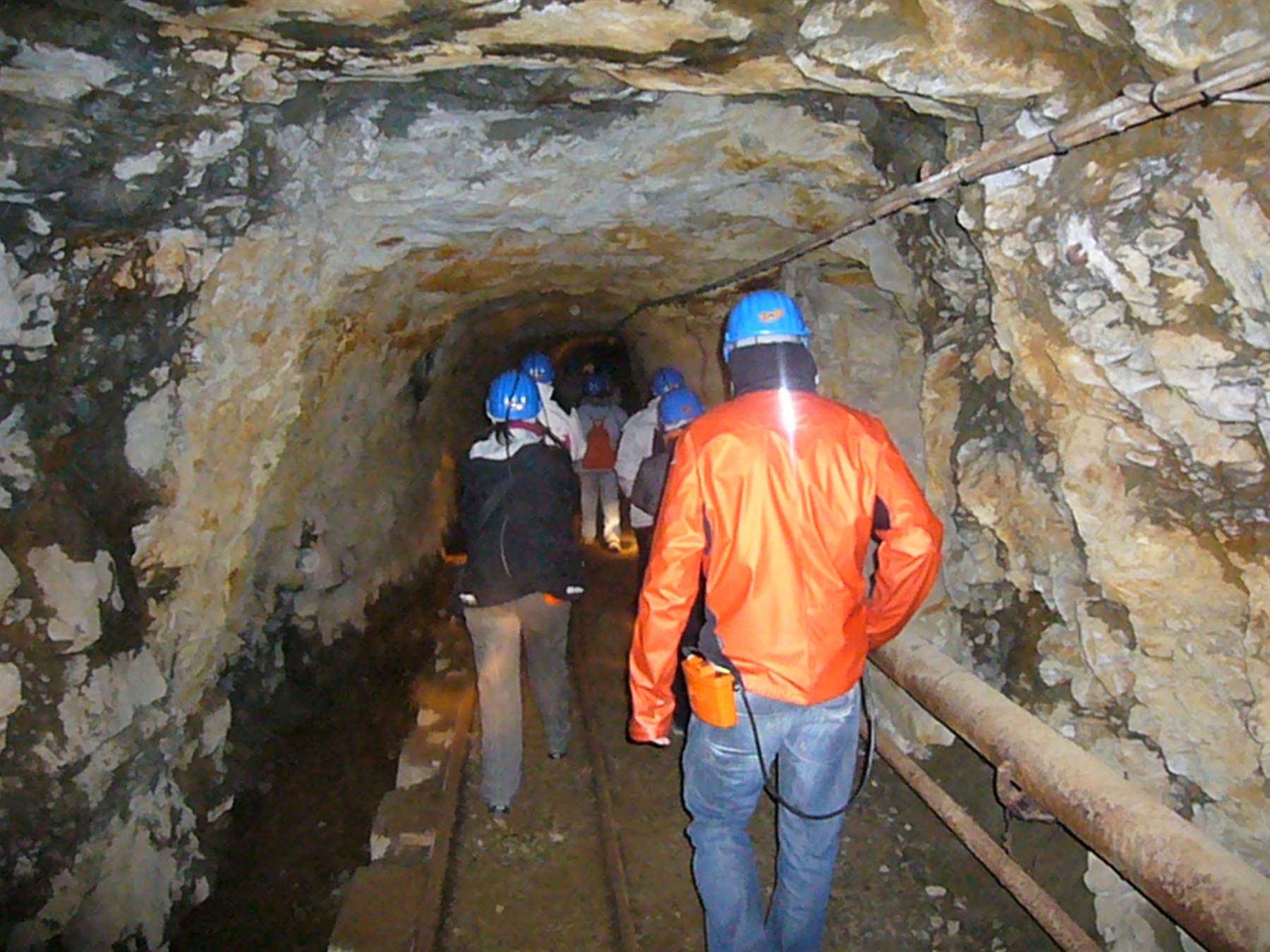 Visitatori con caschi blu attraversano una galleria mineraria scavata nella roccia