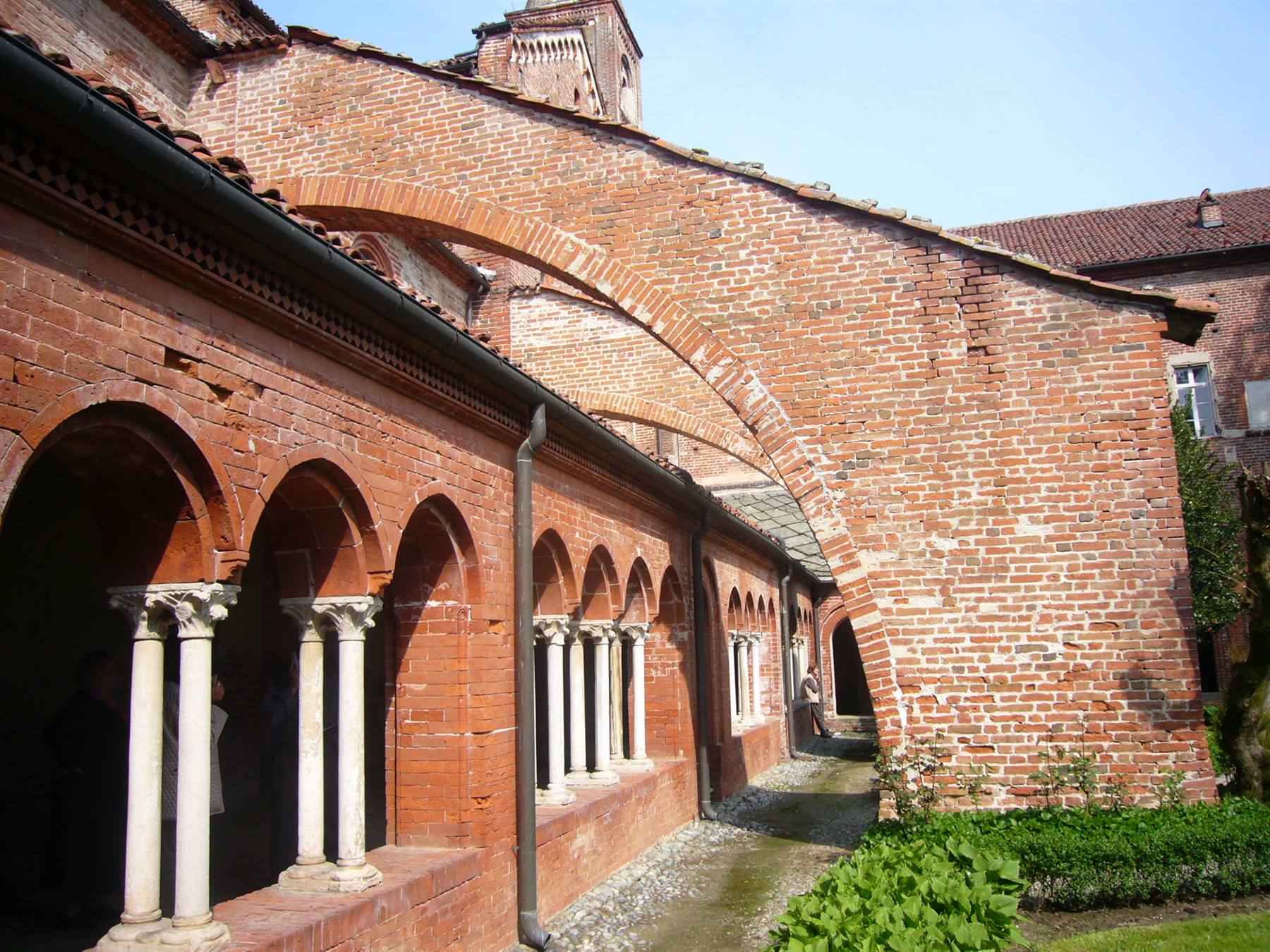 Chiostro in mattoni rossi con arcate e colonnine in marmo bianco, luce diurna