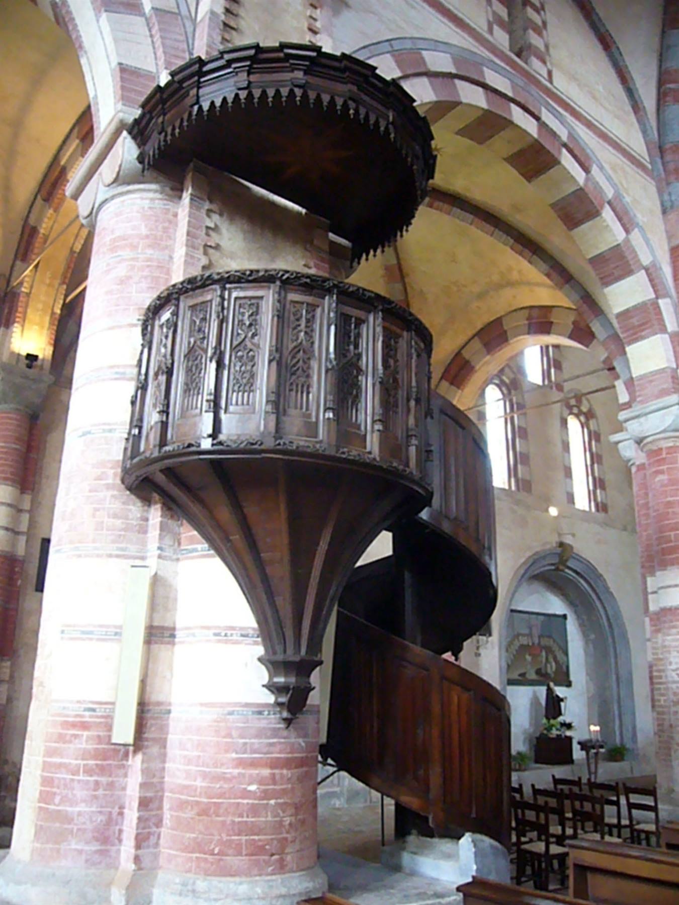 Pulpito ligneo intagliato su colonna in mattoni, chiesa con archi