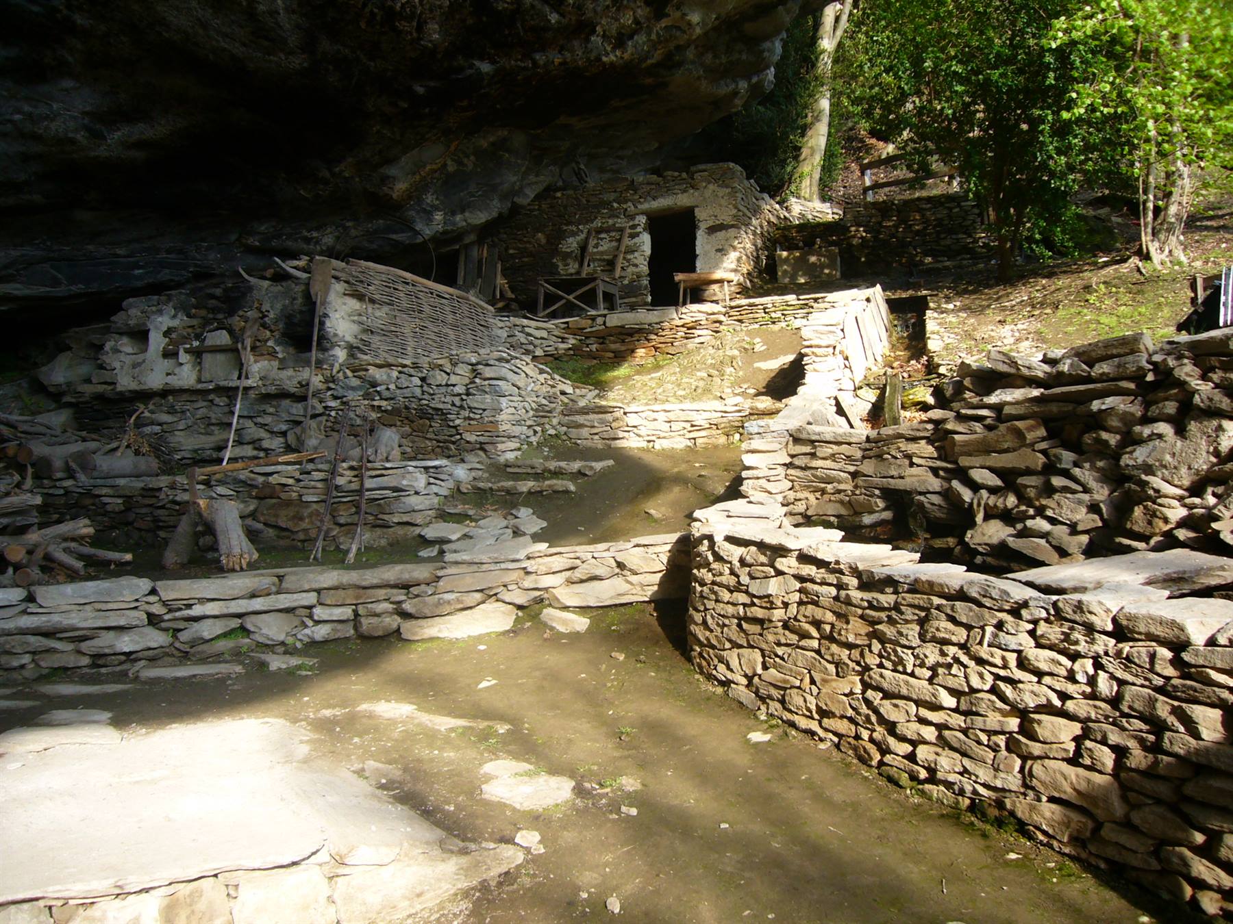 Antico borgo di case in pietra riparato sotto una grande roccia