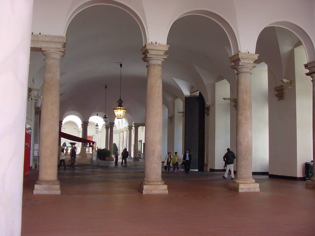 Portico con colonne di pietra e lampadari gialli, passanti sotto le volte