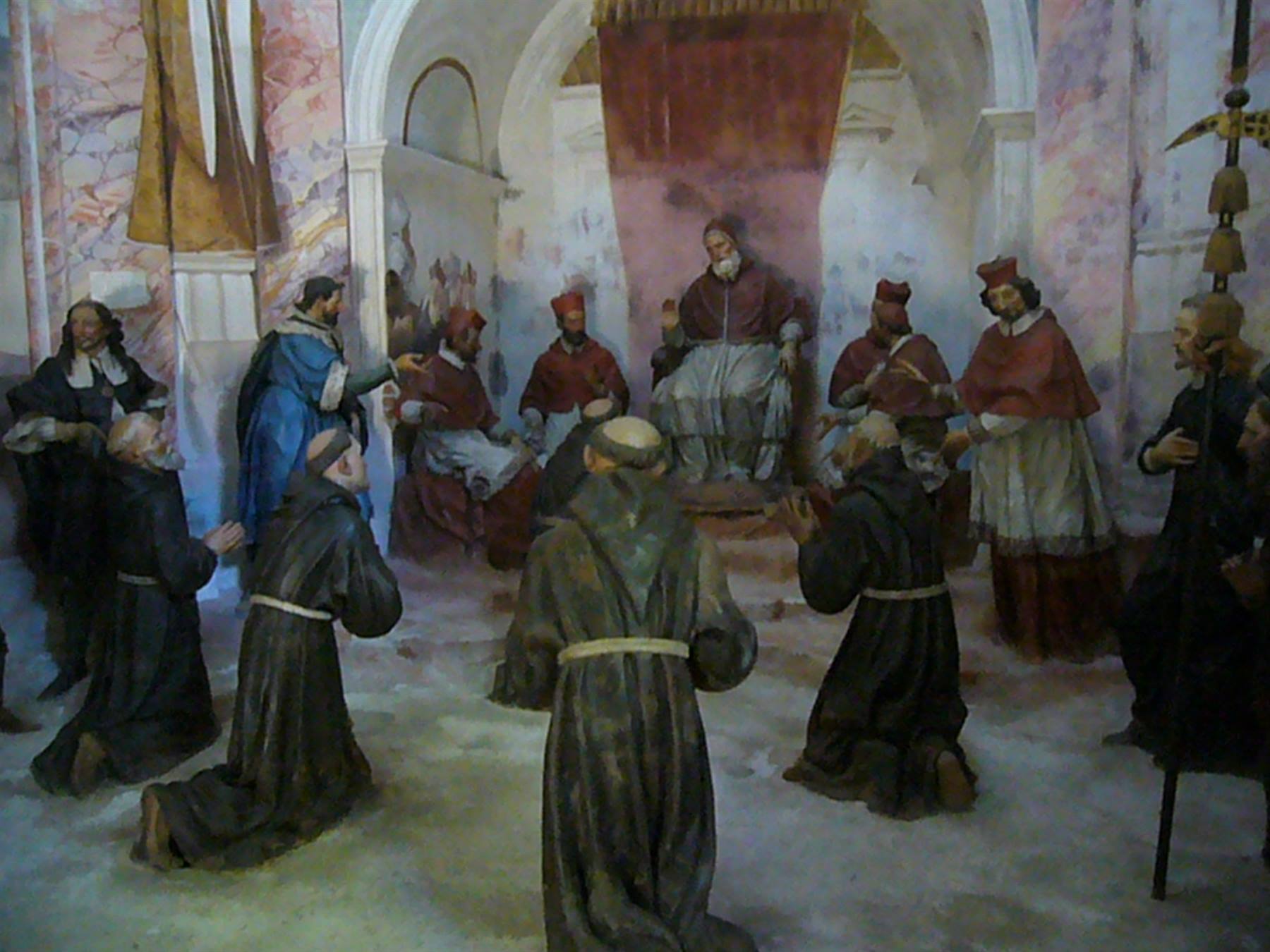Statue di frati inginocchiati davanti al papa e ai cardinali, affreschi chiari