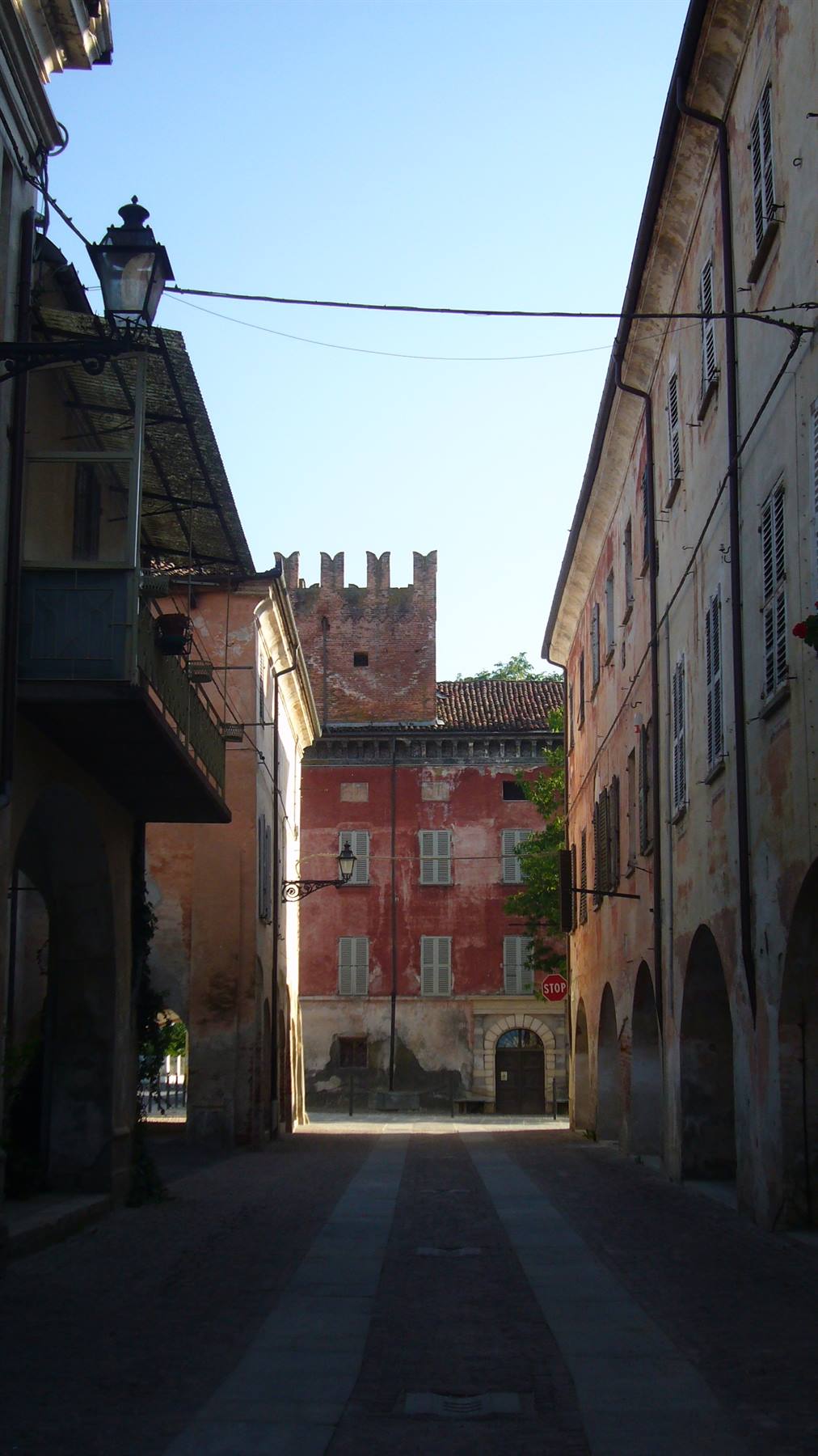 Via lastricata con portici tra case antiche e torre merlata