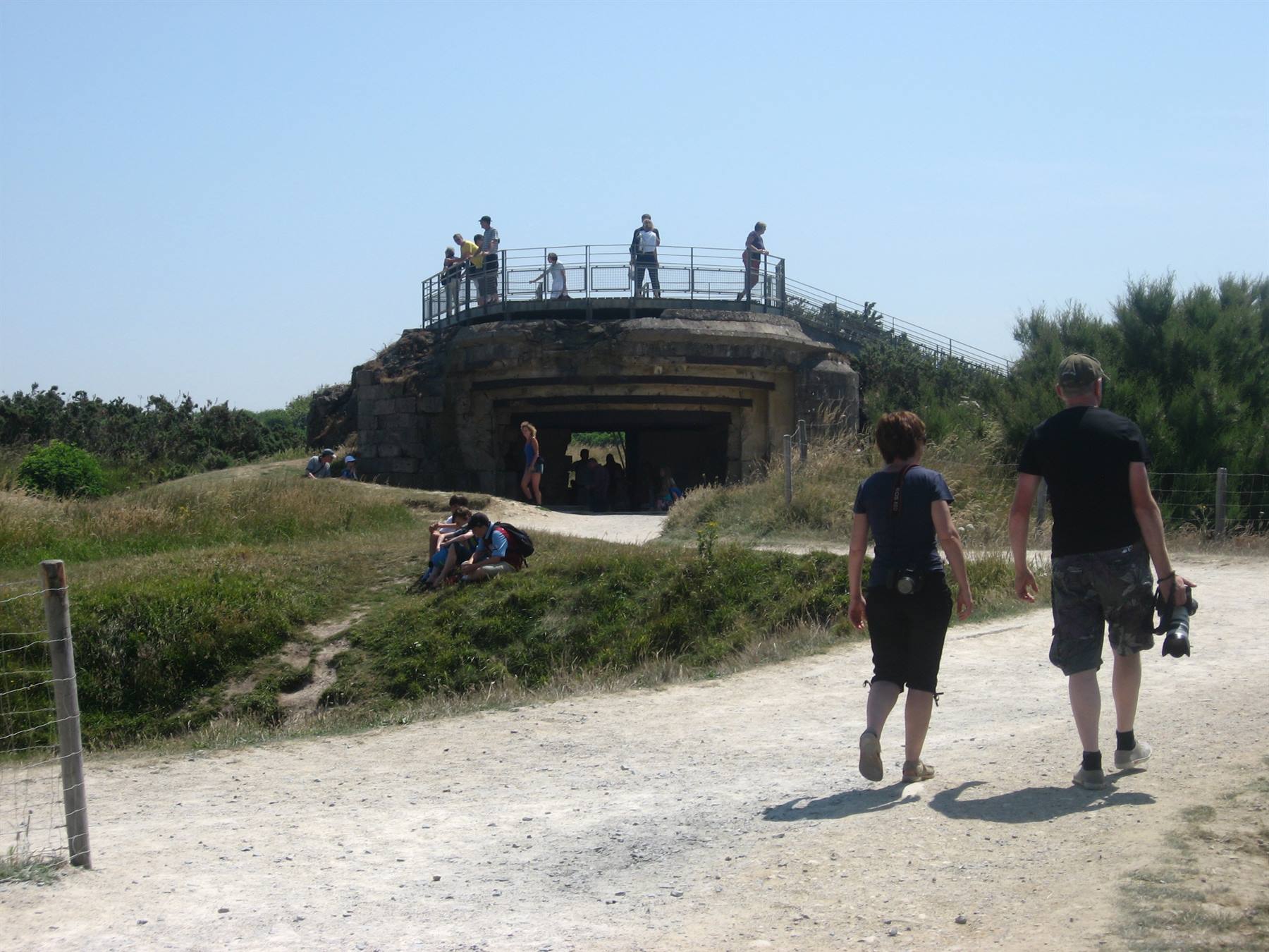 Turisti sul vecchio bunker in cemento di Pointe du Hoc, passeggiata su sentiero sabbioso