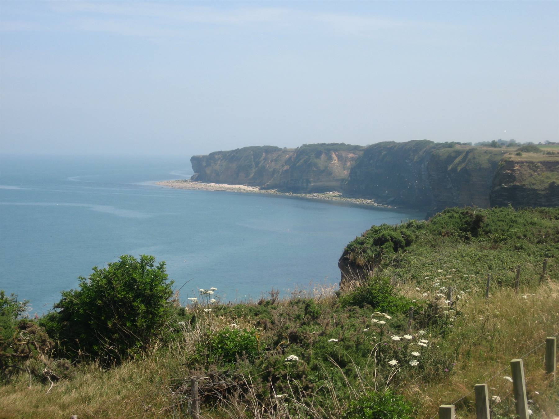 Scogliere calcaree verdeggianti su mare calmo, Pointe du Hoc, Normandia