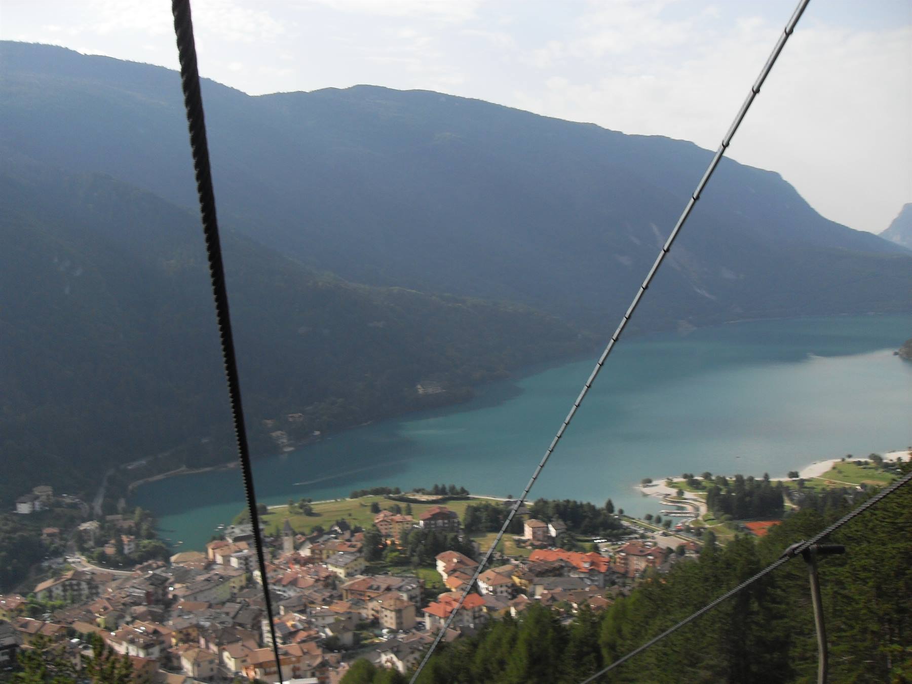 Cavi della funivia sopra il paese e il lago di Molveno tra le montagne