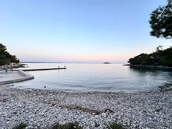 Tramonto rosa sulla baia: il mare calmo e la sera che scende piano.