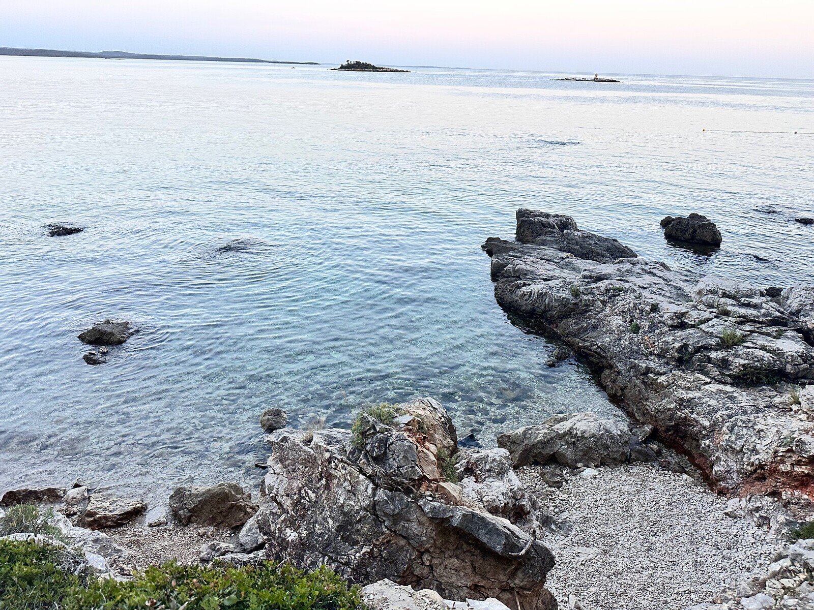Tramonto quieto sul mare cristallino tra gli scogli, un momento sospeso.