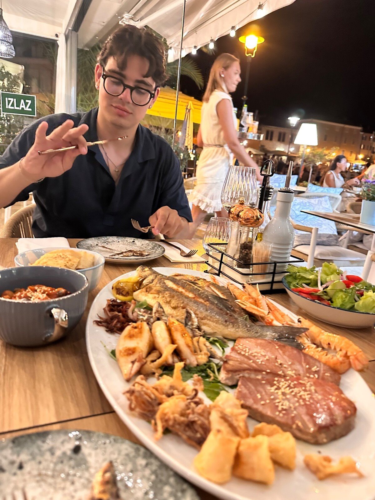Cena di pesce sotto le luci della sera, un piatto gigante da condividere