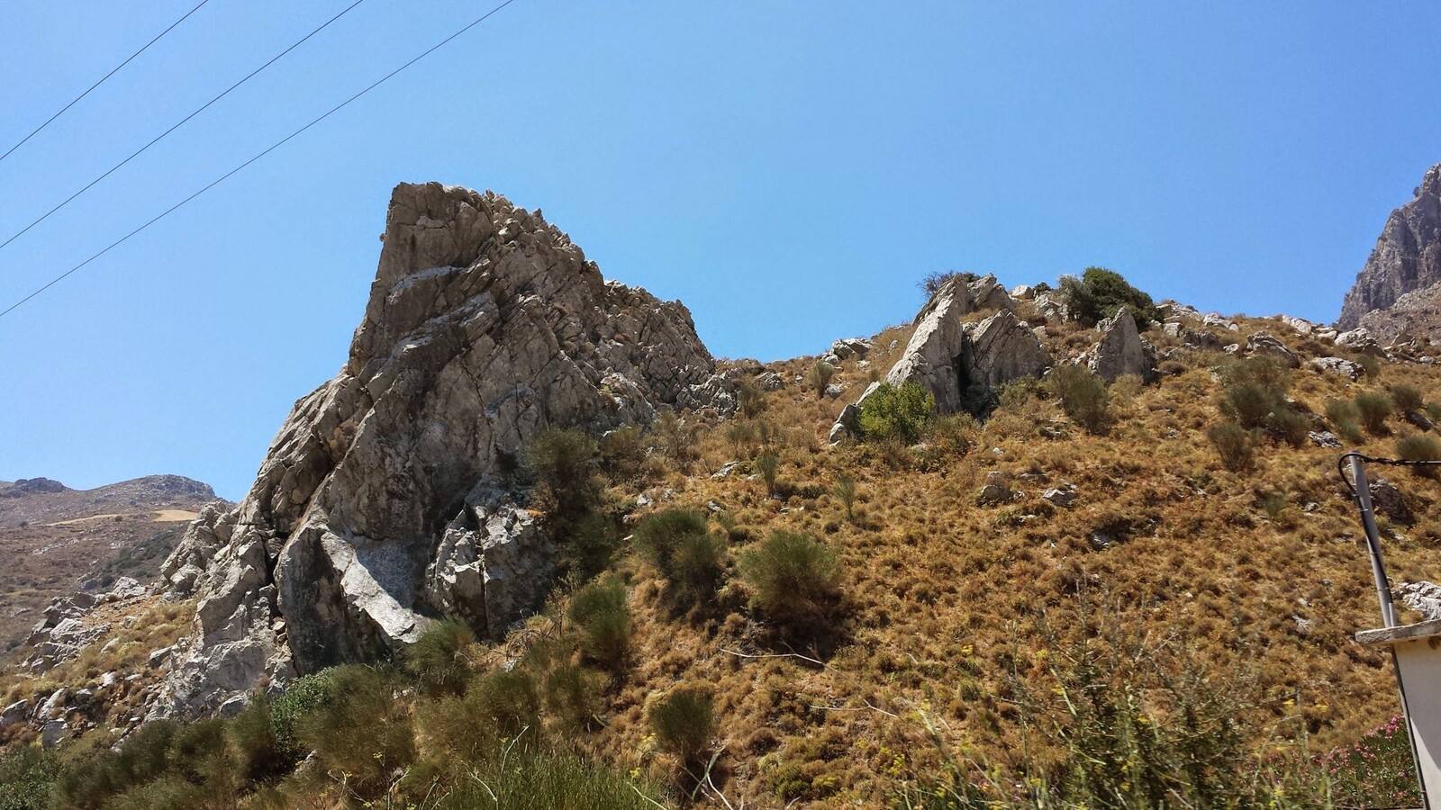 Colline aride e rocce scoscese sotto un cielo azzurro infinito.