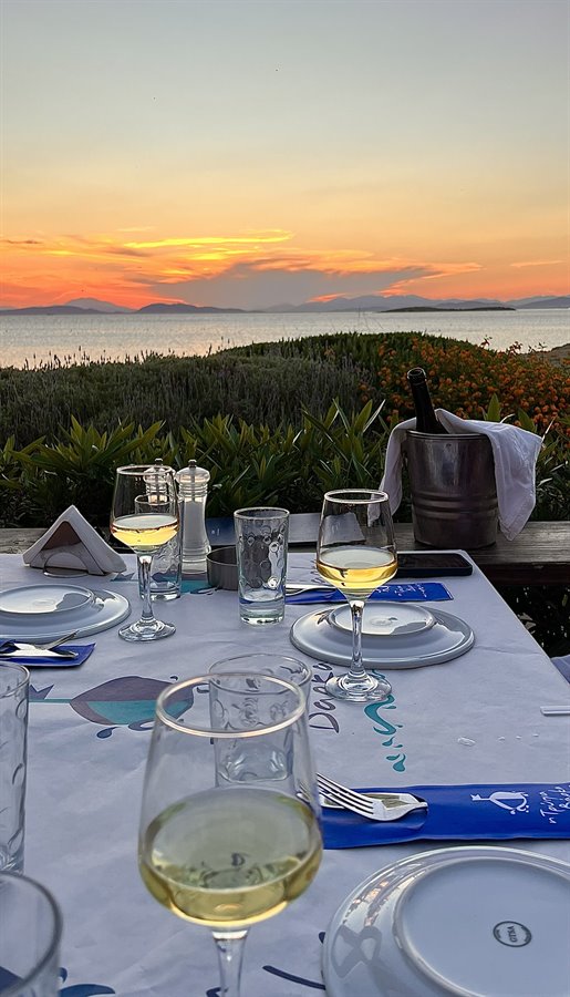 Cena al tramonto, vino bianco e il mare che si tinge d'oro.