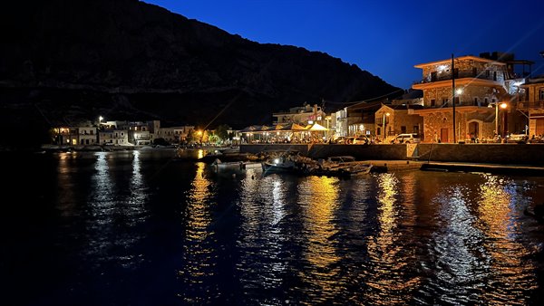 Il porto si accende al tramonto: luci danzanti sull'acqua, cuore felice.