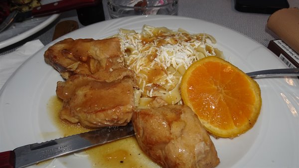 Pranzo in viaggio: pollo, tagliatelle e una fetta d'arancia solare.
