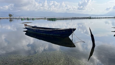 La barca dondola silenziosa, il cielo specchiato nell'acqua calma.