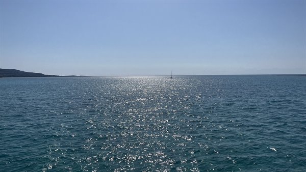 Il mare scintilla d'oro e un'ombra solitaria naviga l'orizzonte.