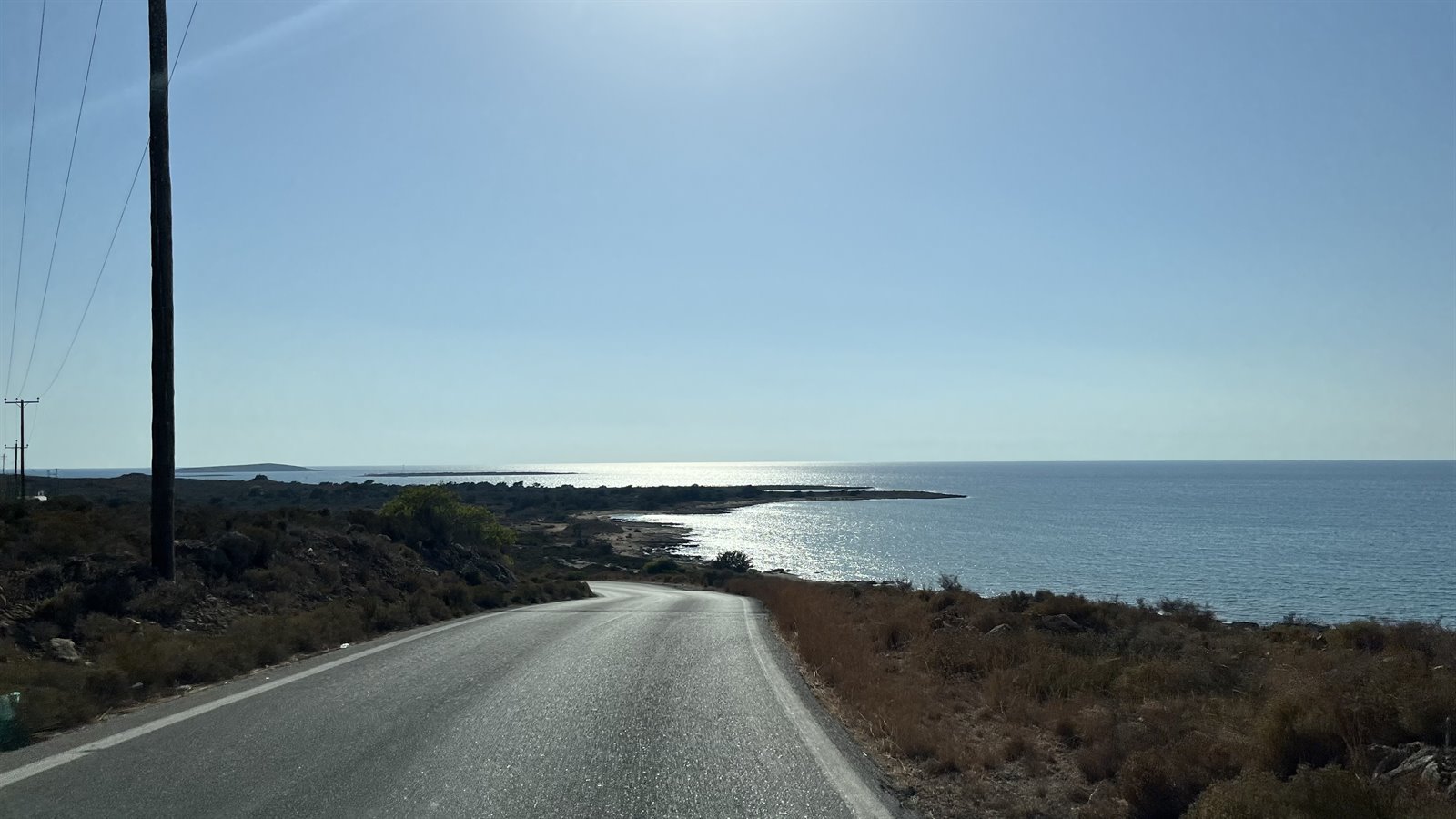 La strada curva verso il mare, il sole danza sull'acqua: che meraviglia.