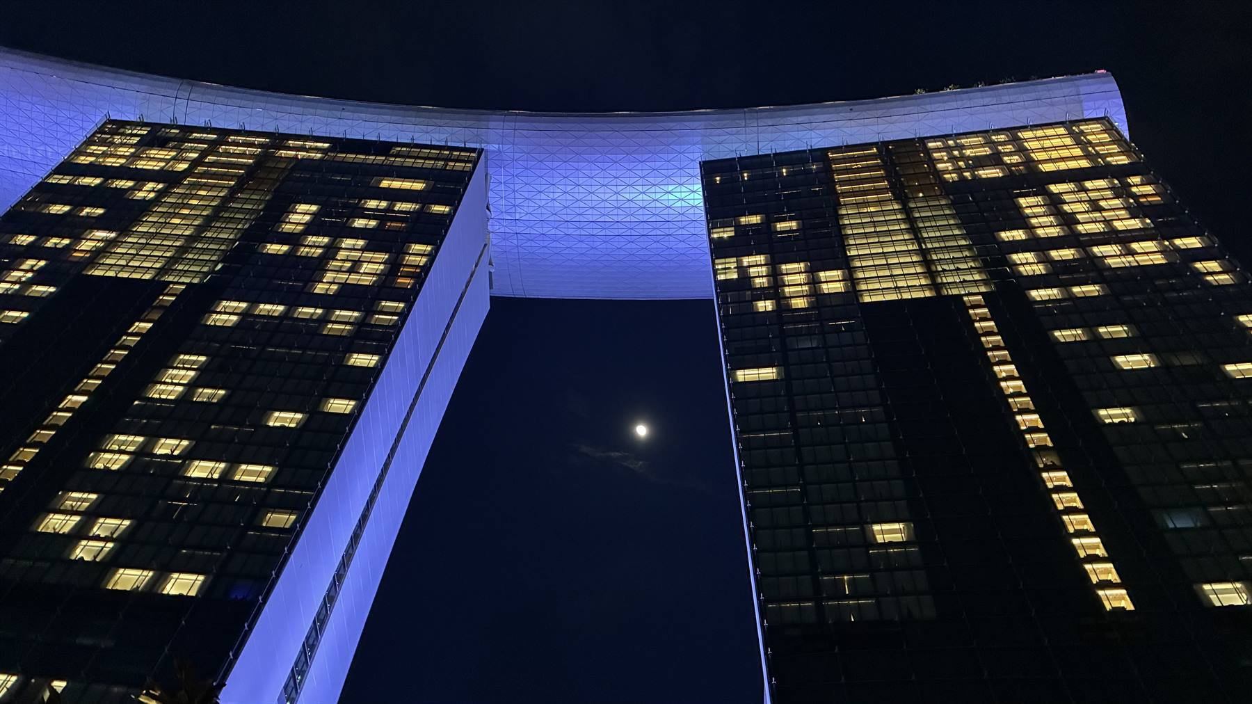 La luna si intravede tra le torri illuminate: Singapore by night.