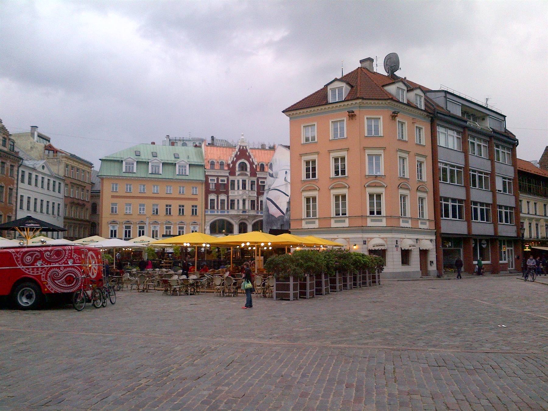 Piazza Dome a Riga, caffè con ombrelloni gialli accanto a case colorate