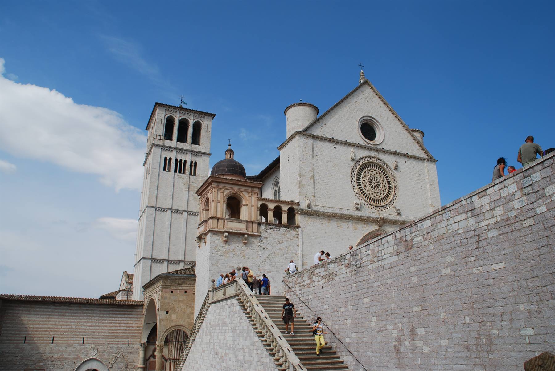 Turisti salgono la scalinata verso la Basilica di San Francesco ad Assisi