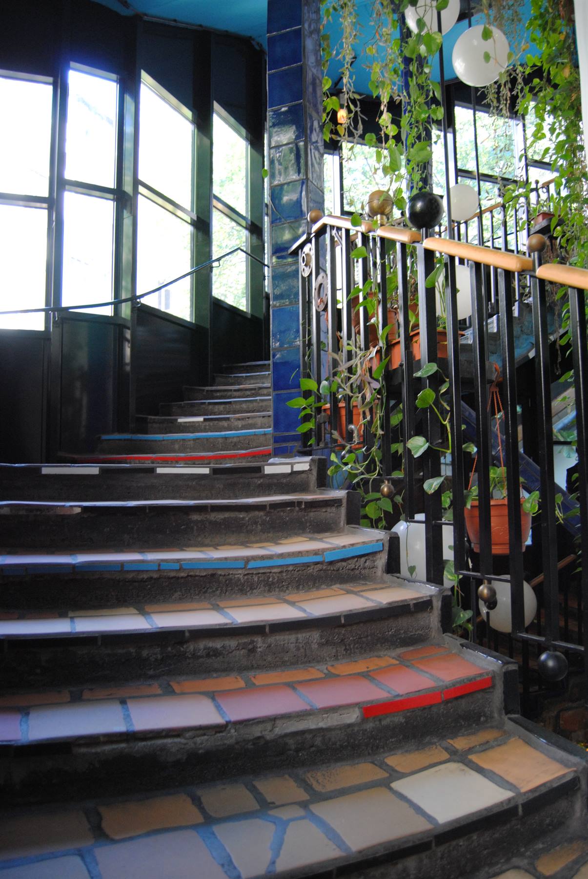 Scala a piastrelle policrome con corrimano nero e piante appese, Hundertwasserhaus