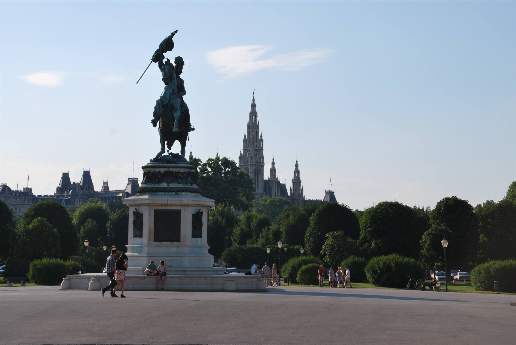 Statua equestre in bronzo a Vienna, con il Rathaus e turisti che passeggiano