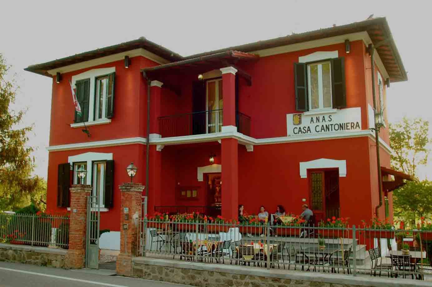 Casa Cantoniera Anas rossa con persone sedute ai tavolini esterni
