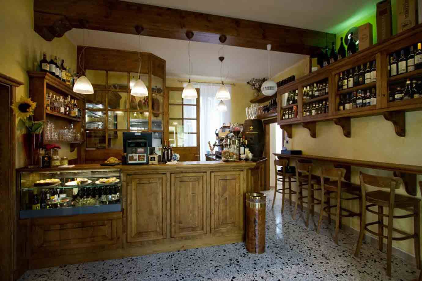 Bar in legno con bancone, bottiglie e sgabelli, luce calda delle lampade