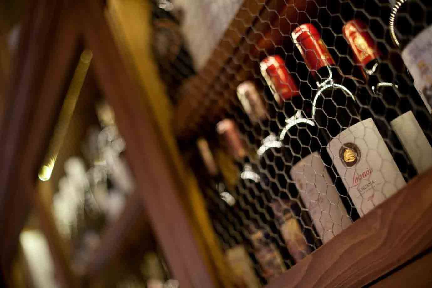 Bottiglie di vino dietro una rete metallica su scaffale di legno