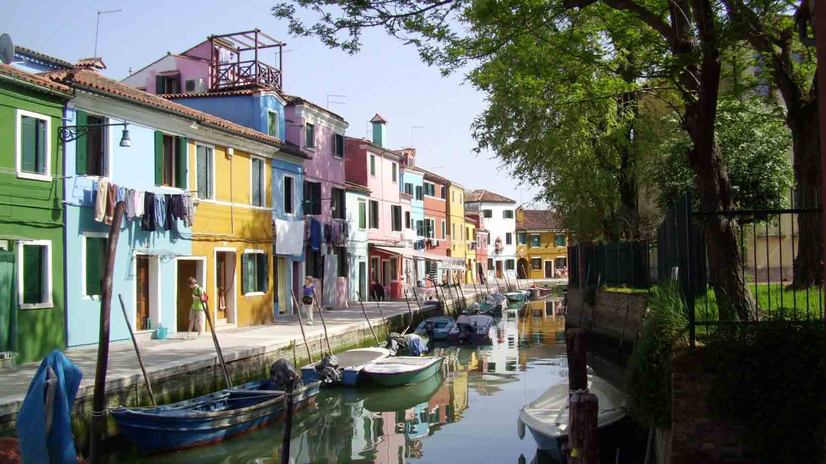 Case colorate lungo il canale di Burano, barche ormeggiate, panni stesi al sole