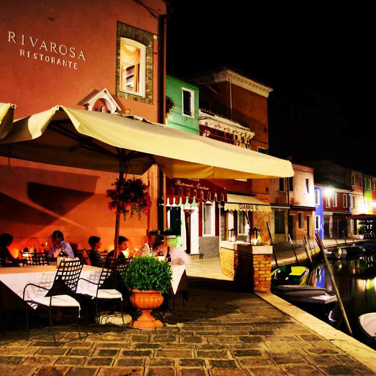 Ristorante Riva Rosa a Burano: tavoli sotto ombrellone, case colorate e barche sul canale
