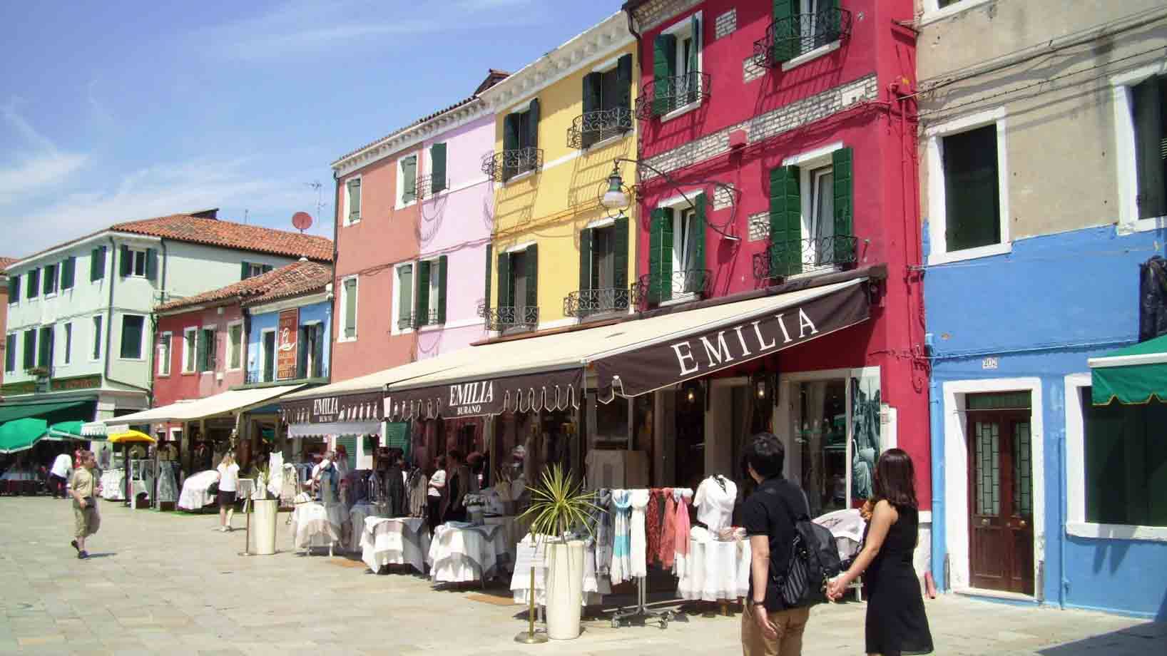 Case colorate e mercatino di pizzi sotto i tendoni, turisti passeggiano a Burano