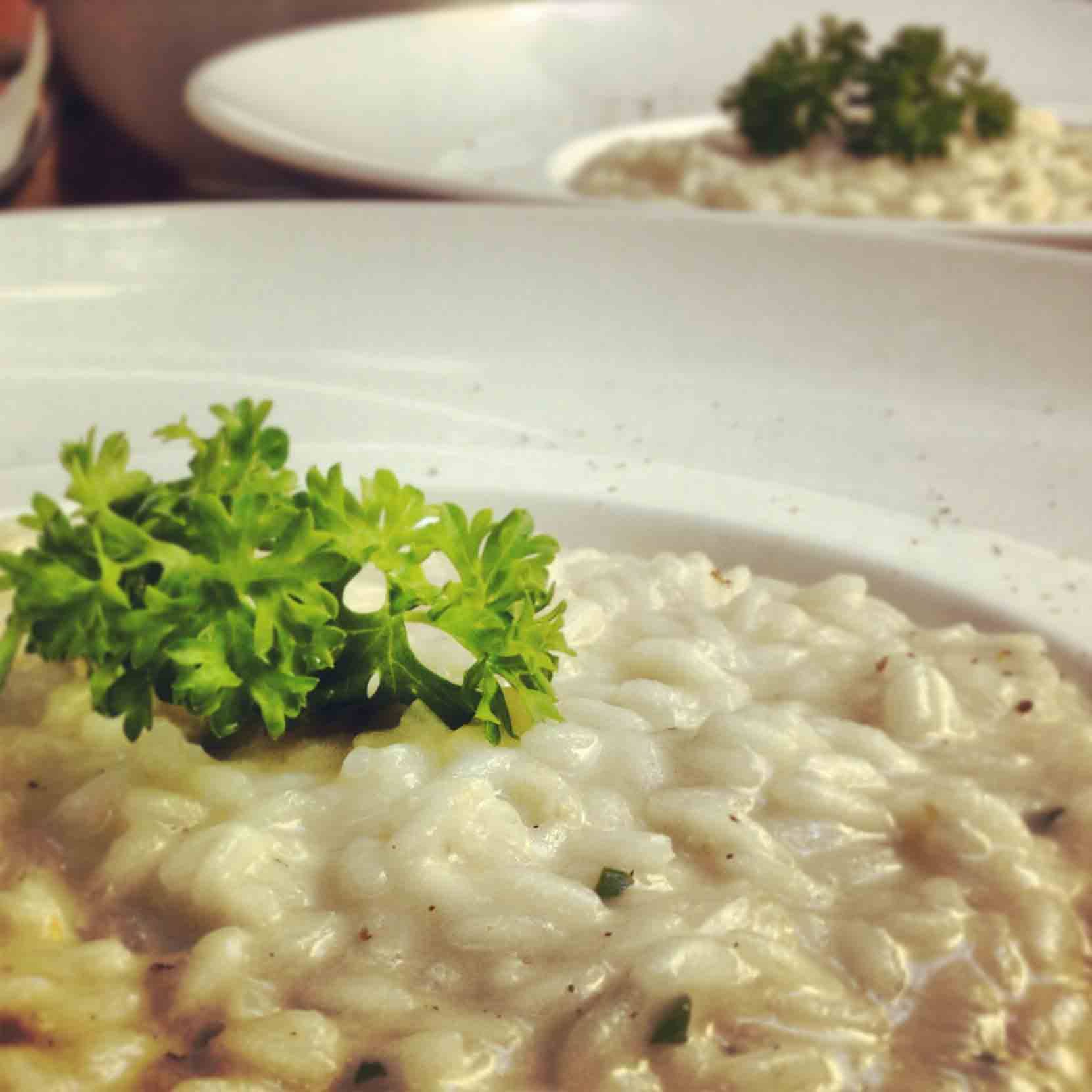 Risotto cremoso nei piatti bianchi, guarnito con prezzemolo fresco