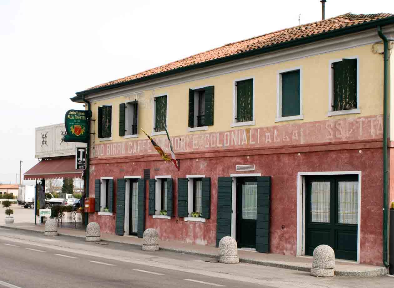 Antica trattoria con insegna e scritta d'epoca, striscioni lungo la strada
