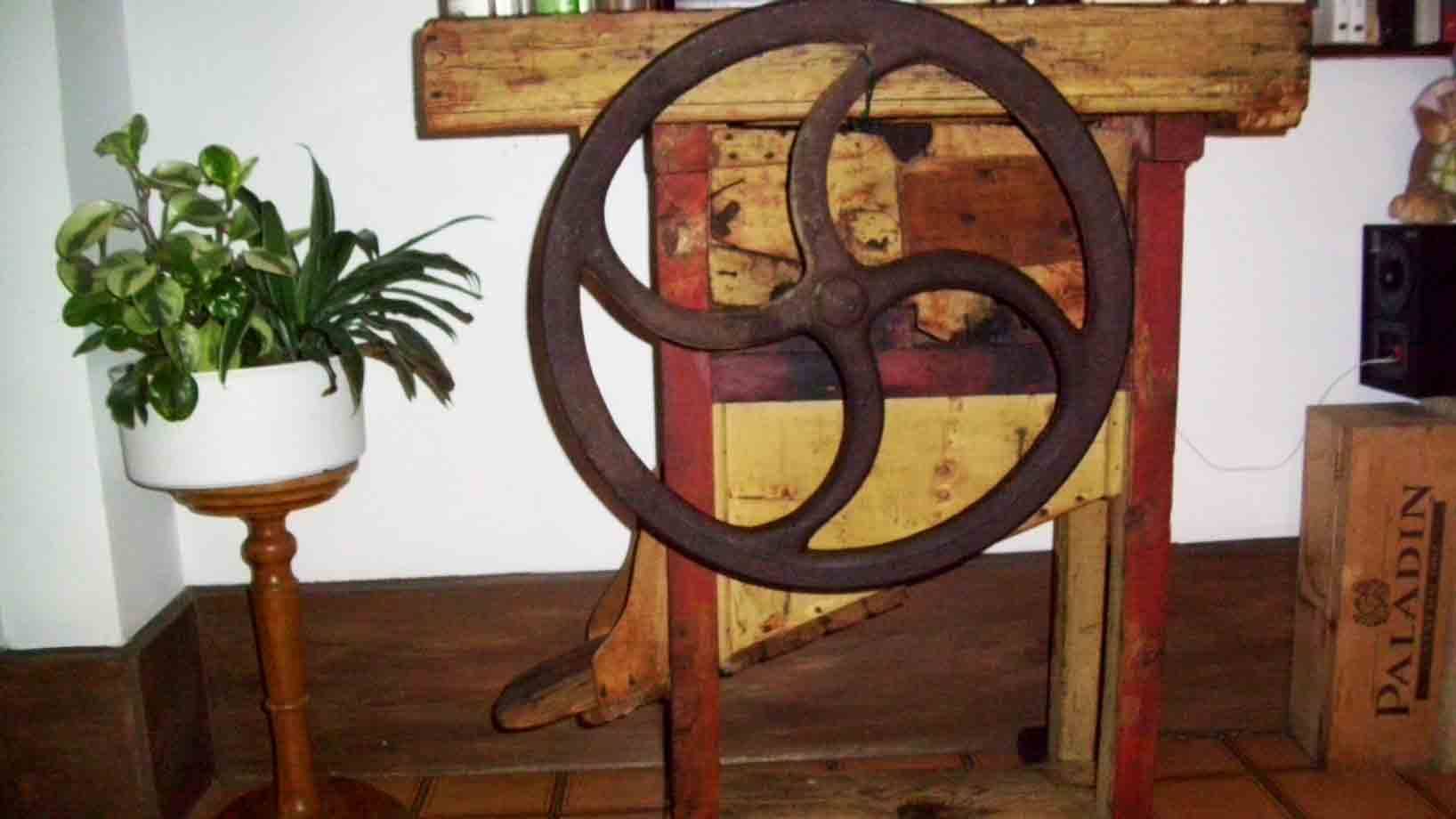 Ruota in ghisa su macchina agricola di legno, vaso con pianta accanto
