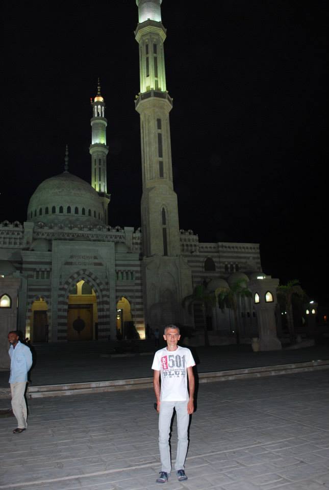 Turista in maglietta bianca davanti alla moschea Al Sahaba illuminata di notte