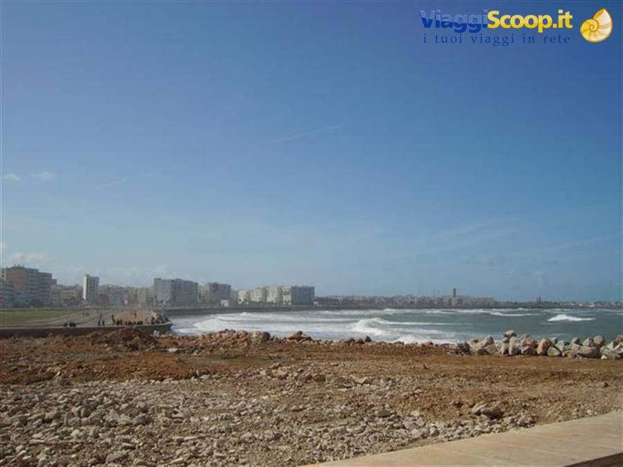 Onde sull'oceano davanti agli edifici della città, scogliera in primo piano