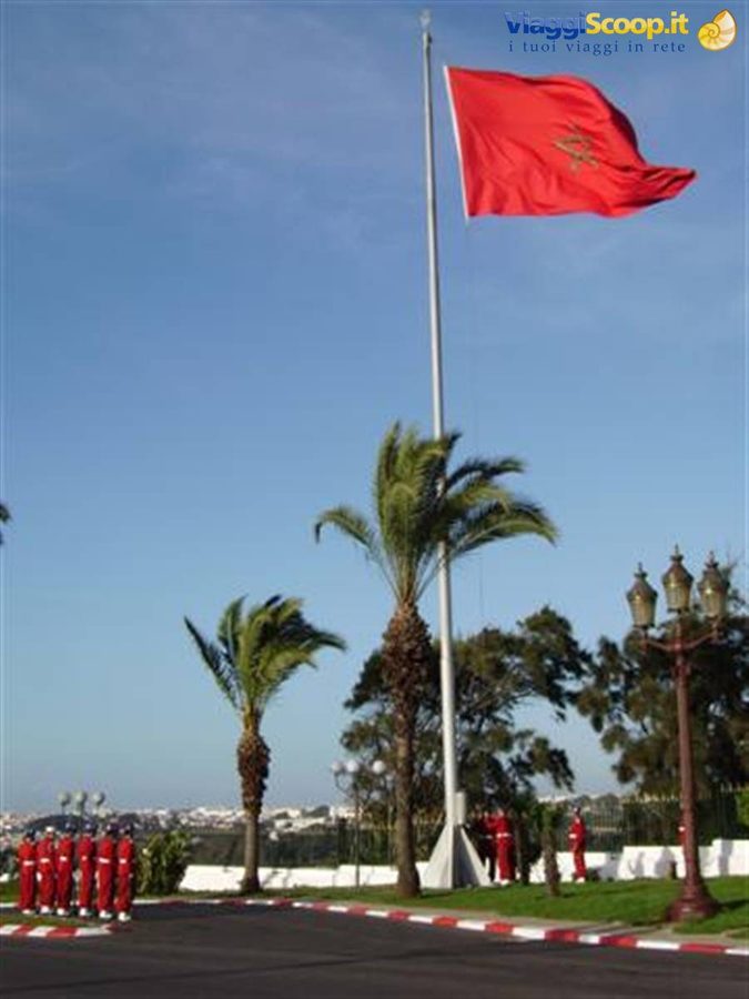 Guardia in uniforme rossa sotto la bandiera del Marocco davanti al Palazzo Reale di Rabat