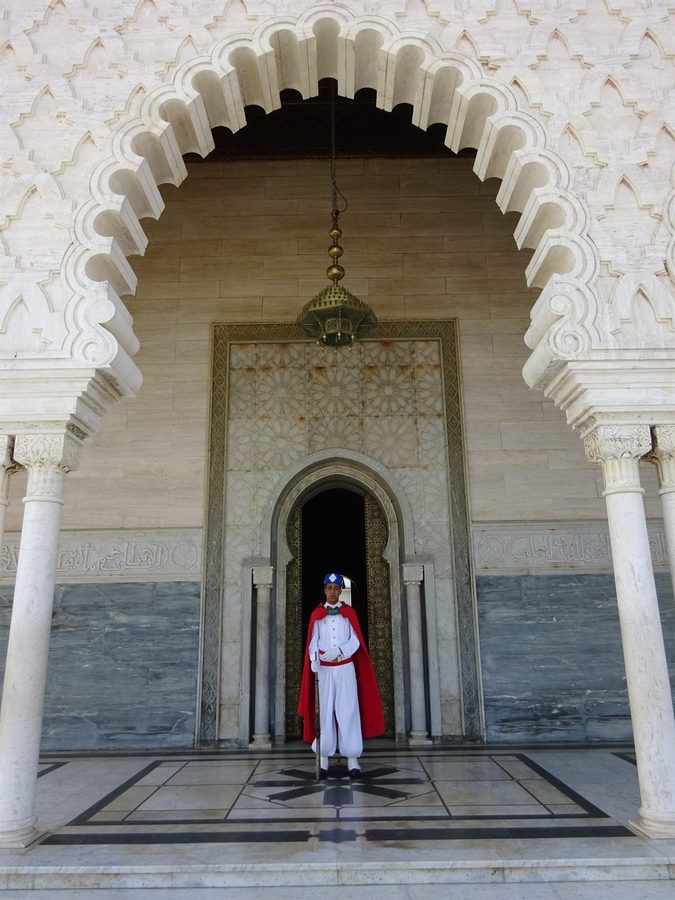 Guardia in divisa bianca e mantello rosso sotto l'arco del Mausoleo Mohammed V, Rabat