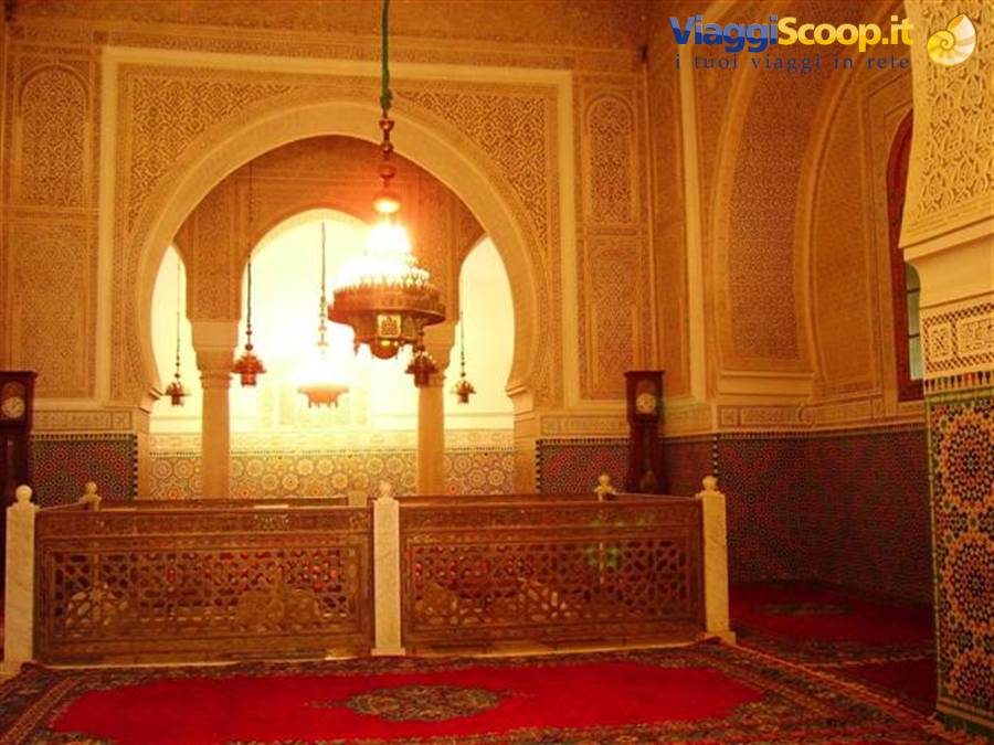 Interno di mausoleo a Meknes: lampadari accesi, stucchi intagliati, zellige e recinzioni in legno