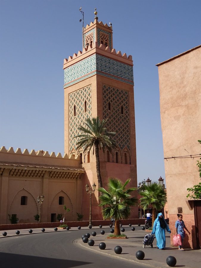 Donna in blue passa davanti al minaretto decorato della moschea della Kasbah, Marrakech
