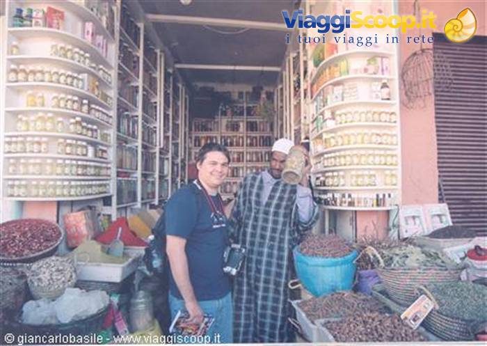 Turista con macchina fotografica accanto al venditore nel souk delle spezie di Marrakech