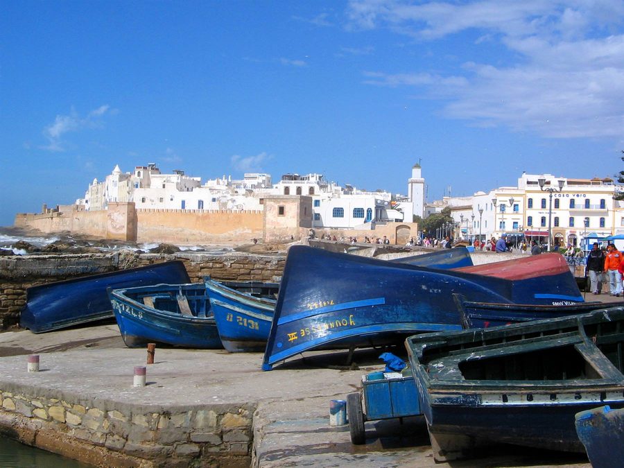 Barche blu capovolte sul molo di pietra davanti alle mura di Essaouira