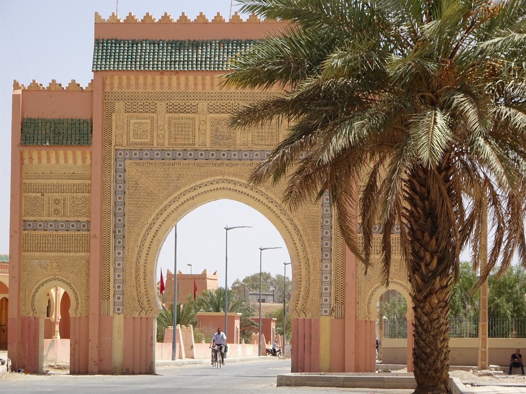 Porta monumentale in mattoni e zellige a Er Rachidia, ciclista sotto l'arco